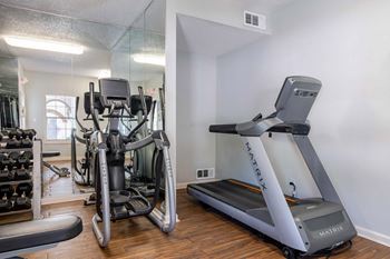 A treadmill and a stationary bike are in a well lit room.